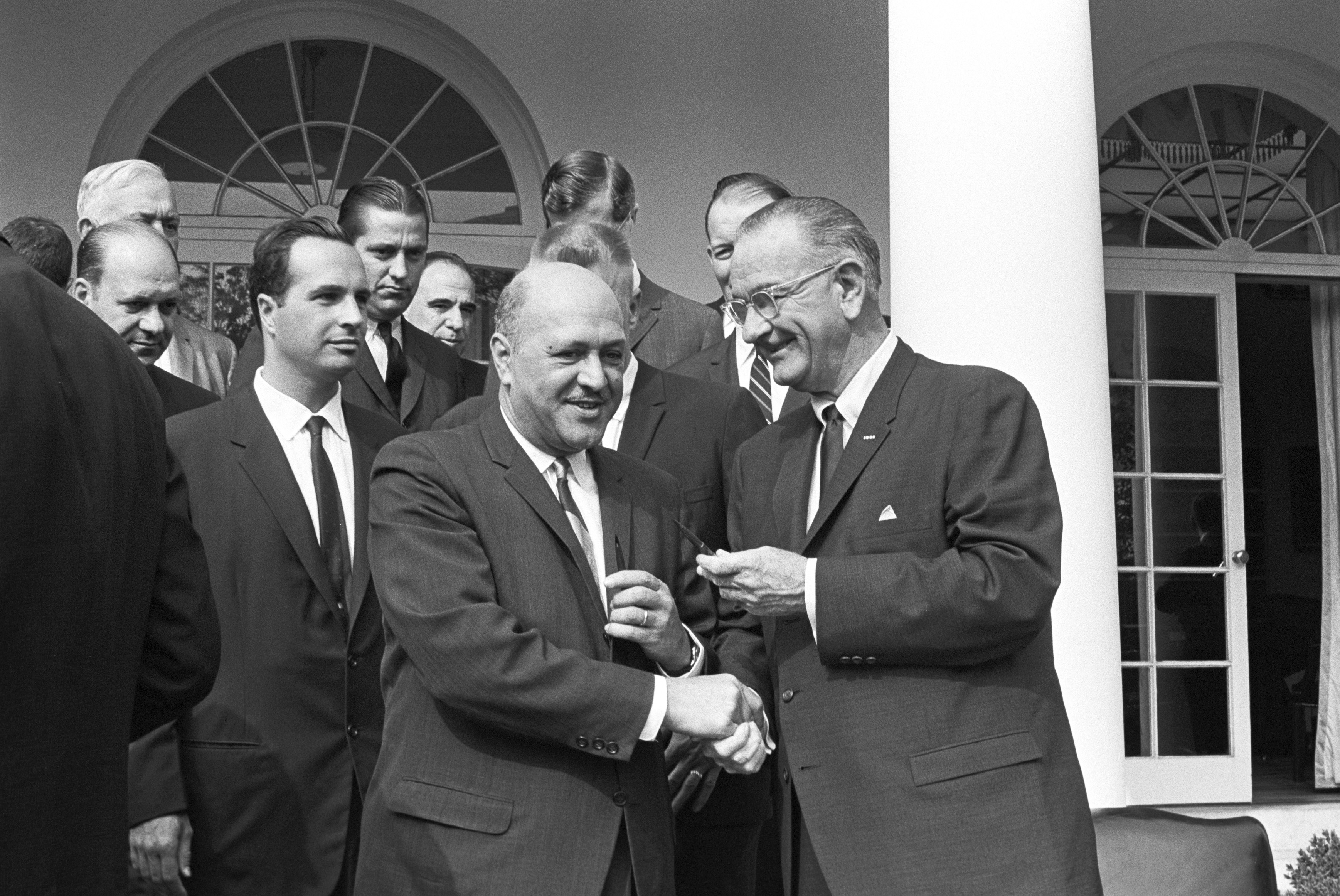 President Lyndon B. Johnson shaking hands with Robert C. Weaver after signing the HUD bill. (Weaver served as the first Secretary of HUD.)