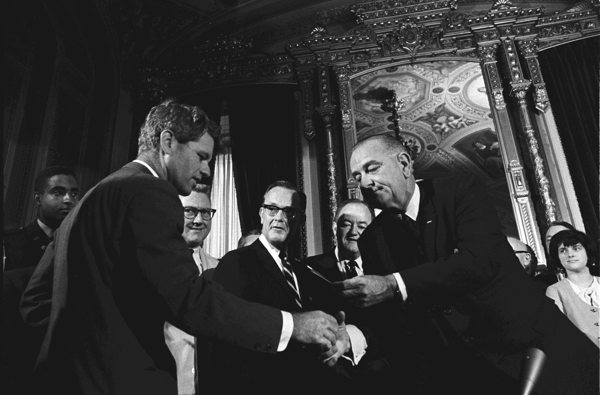 President Lyndon B. Johnson hands Senator Robert F. Kennedy a pen from the signing.