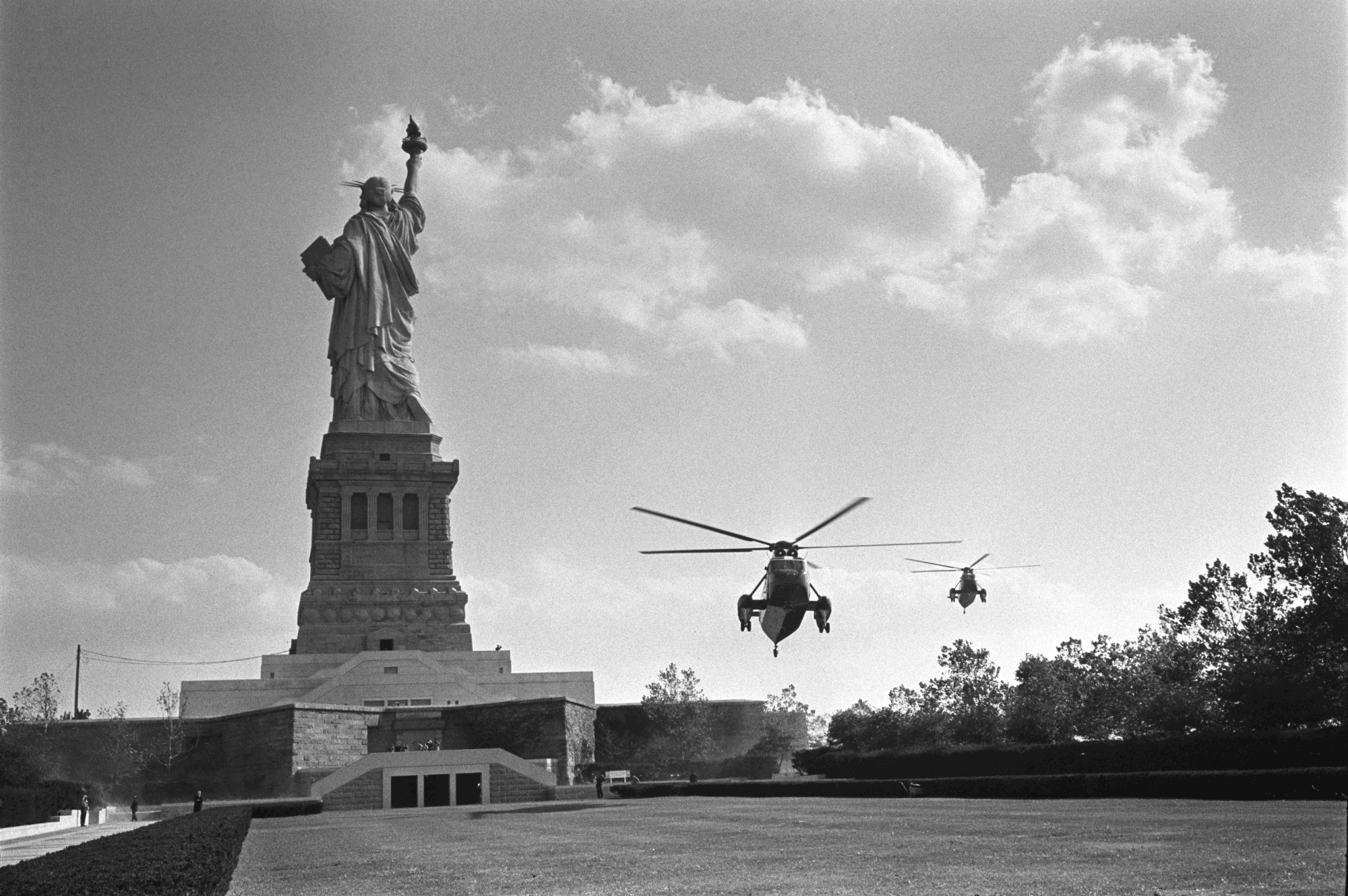 Two helicopters carrying President Lyndon B. Johnson and other officials prepare to land on Liberty Island.