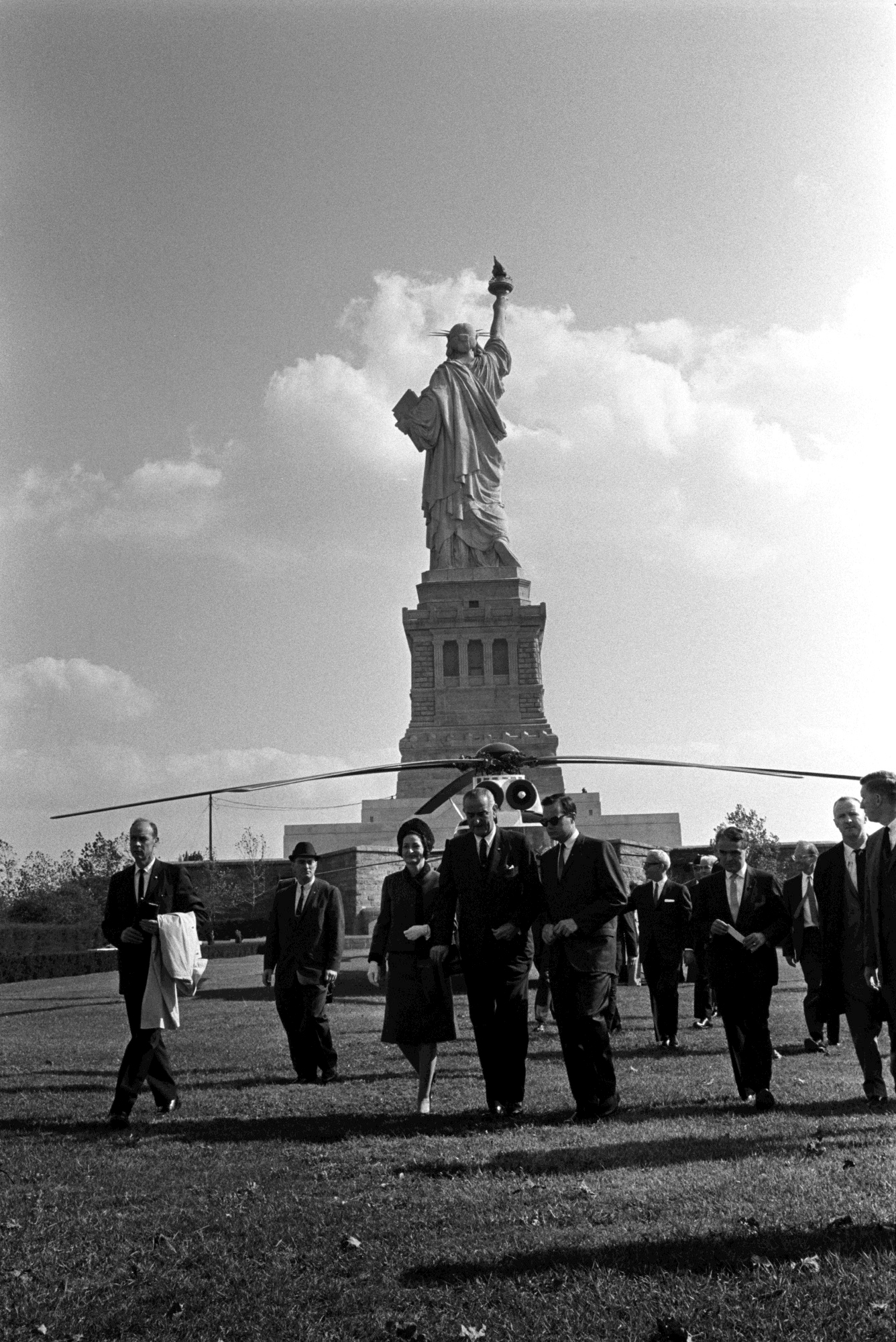 Lady Bird Johnson and President Lyndon B. Johnson make their way to the signing. L-R: Rufus Youngblood, unidentified, Lady Bird Johnson, President Lyndon B. Johnson, Bill Moyers, Arthur Goldberg (back), Jack Valenti, McGeorge Bundy (back), unidentified.