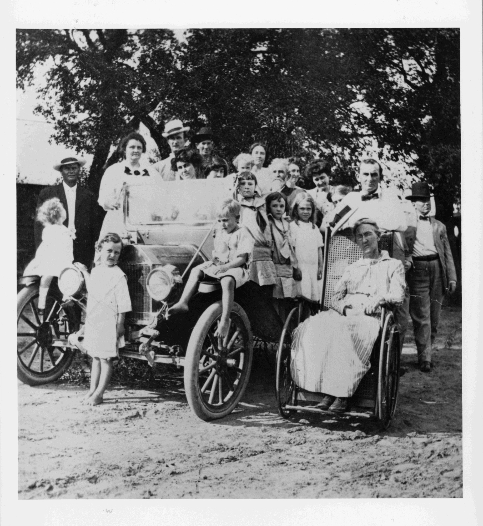 Group photo of the Johnson family with all posed around an automobile.