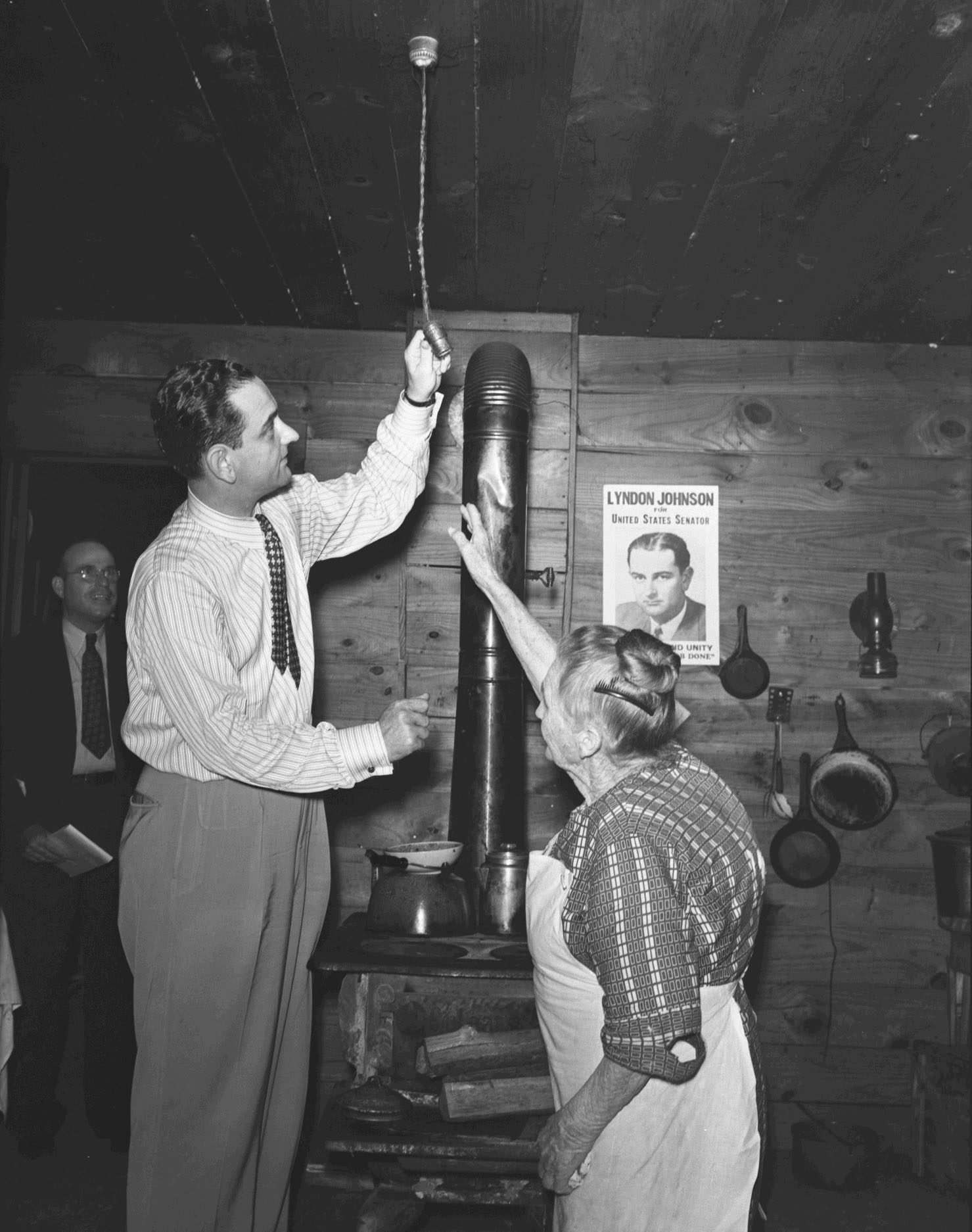 Congressman Lyndon B. Johnson and Mrs. Mattie Malone examine an electric light fixture.