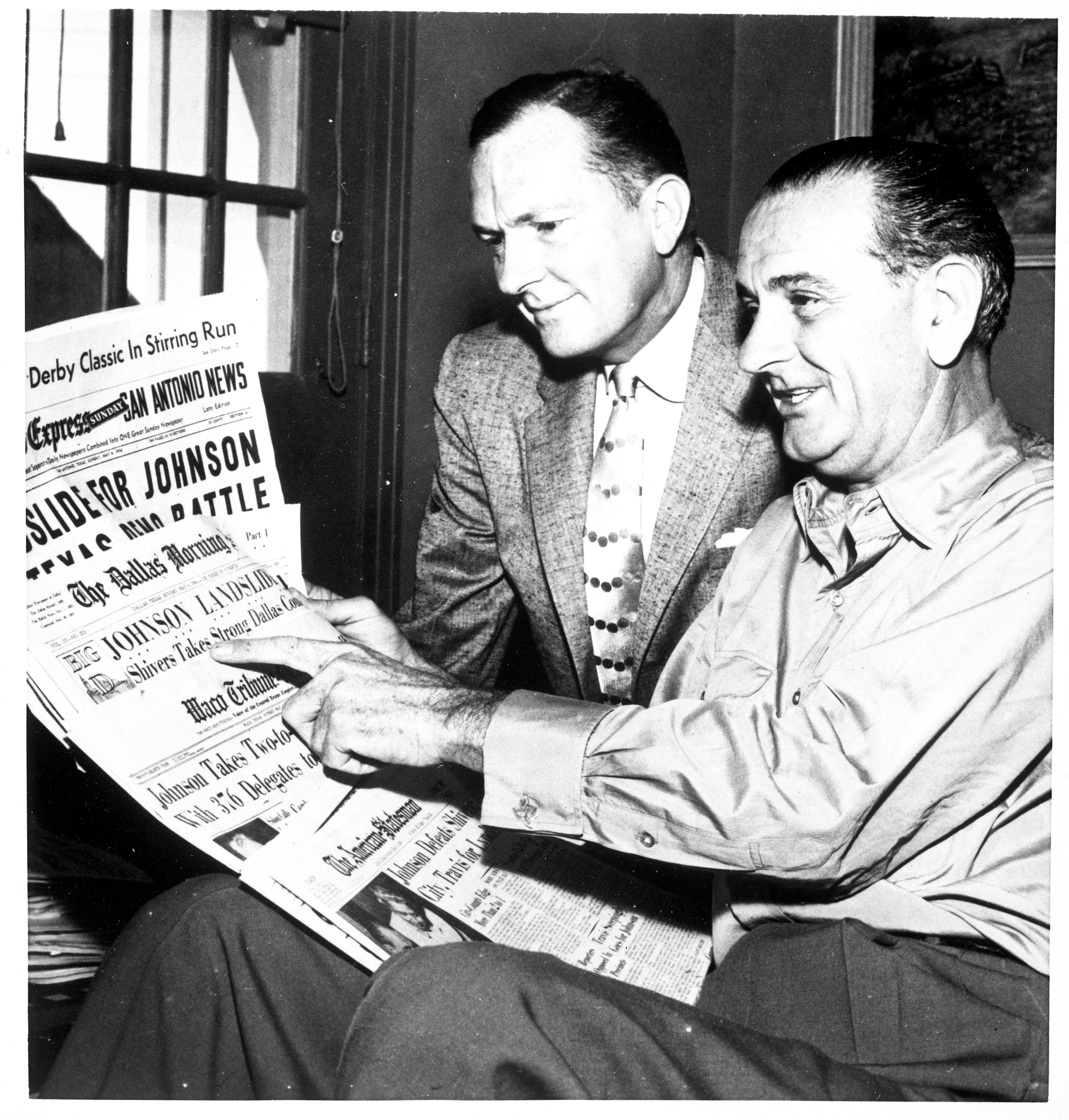 Sen. Lyndon B. Johnson and his brother Sam Houston Johnson look at newspaper headlines proclaiming LBJ's victory. 