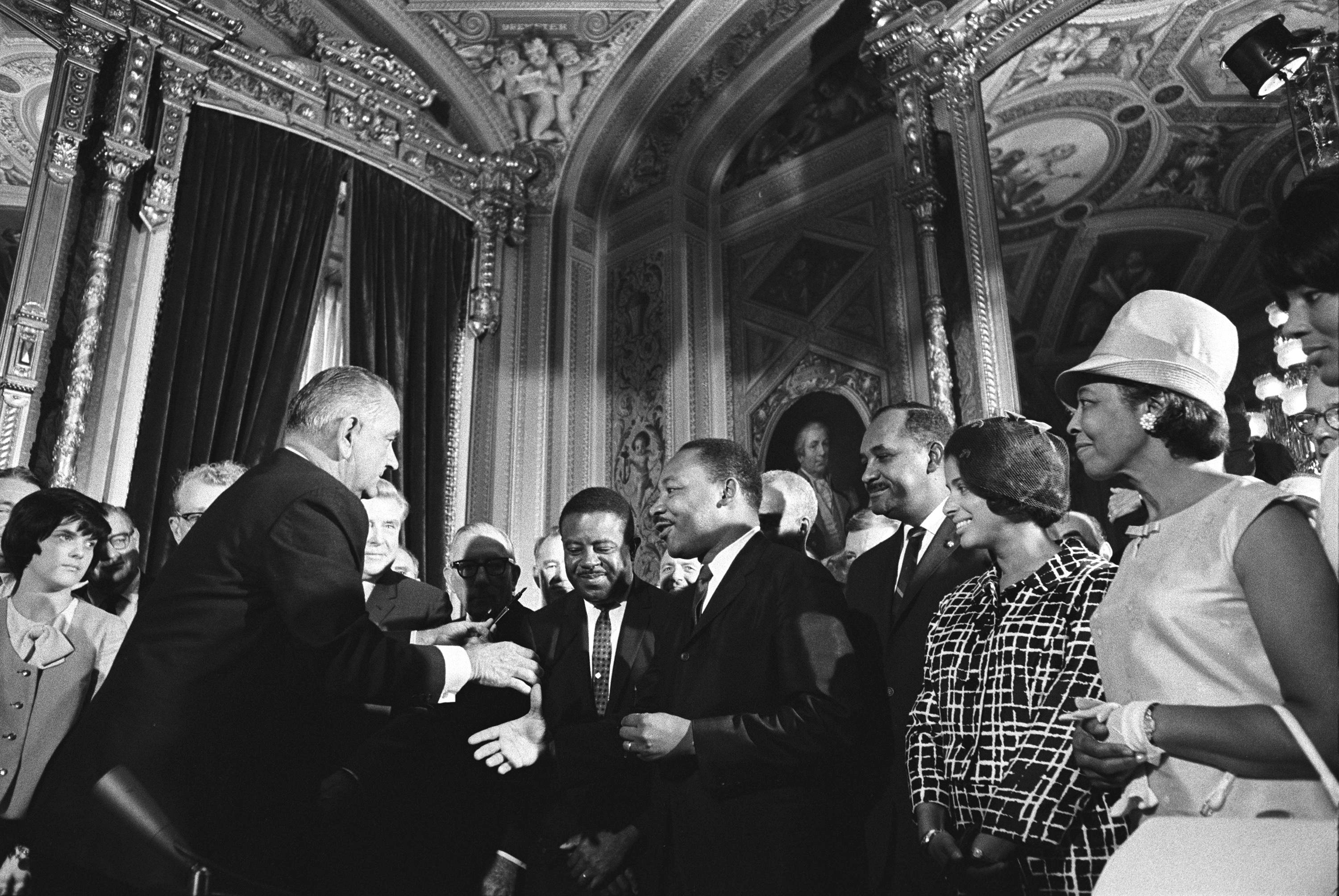 President Lyndon B. Johnson moves to shake hands with Dr. Martin Luther King while others look on. LBJ Library photo by Yoichi Okamoto #A1030-17A.