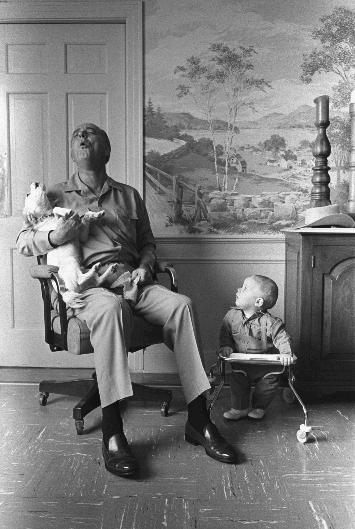 President Johnson, sitting in a chair, sings with his dog, Yuki, while his grandson, Patrick Lyndon Nugent, looks on.