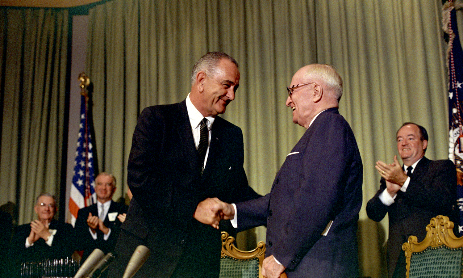 President Lyndon B. Johnson shakes hands with President Harry S. Truman as others (in background) applaud, LBJ Library photo by Unknown, 34897-14