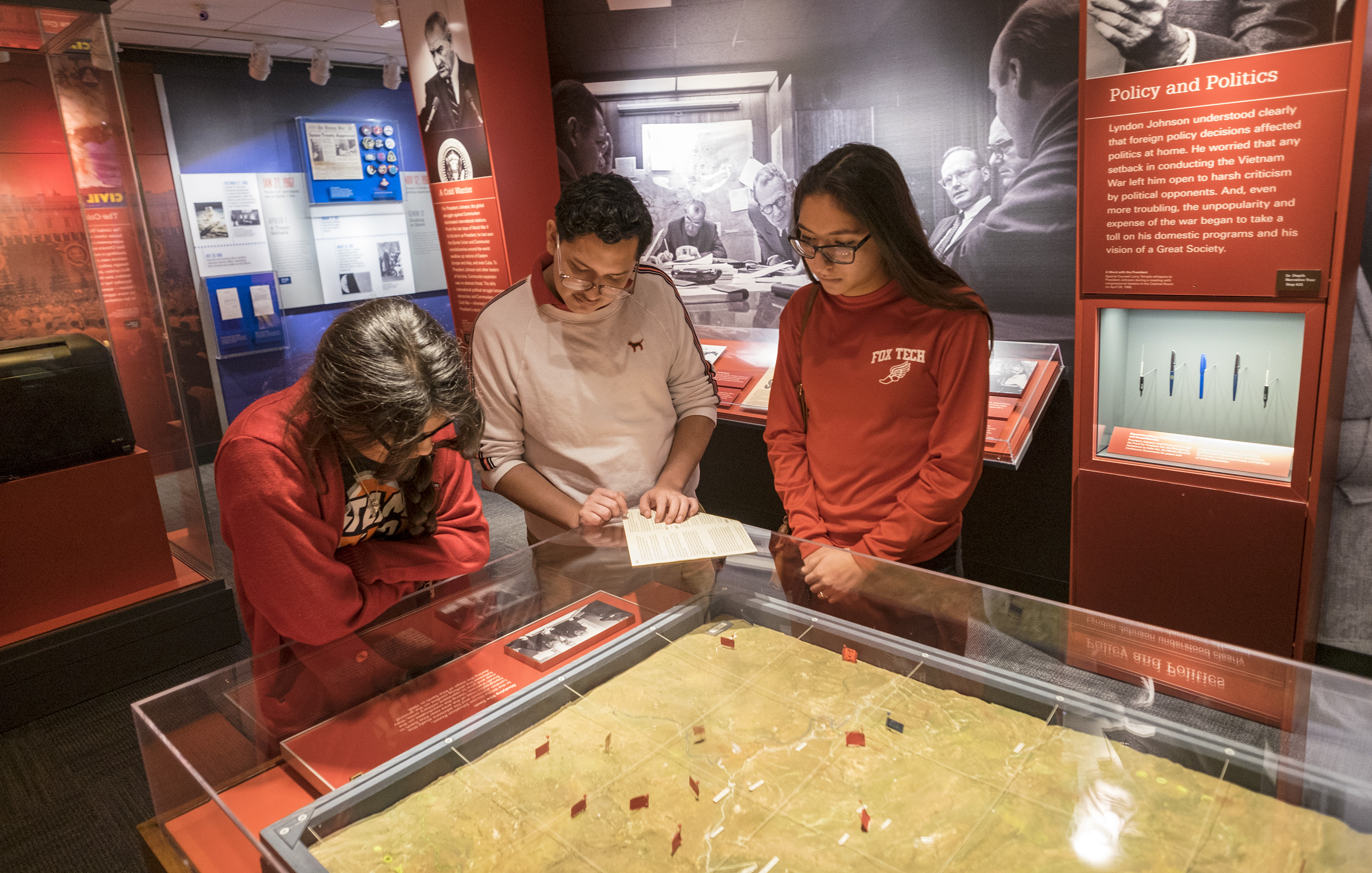 Three high school students read the label on a map in the Vietnam War exhibition at the LBJ Library.
