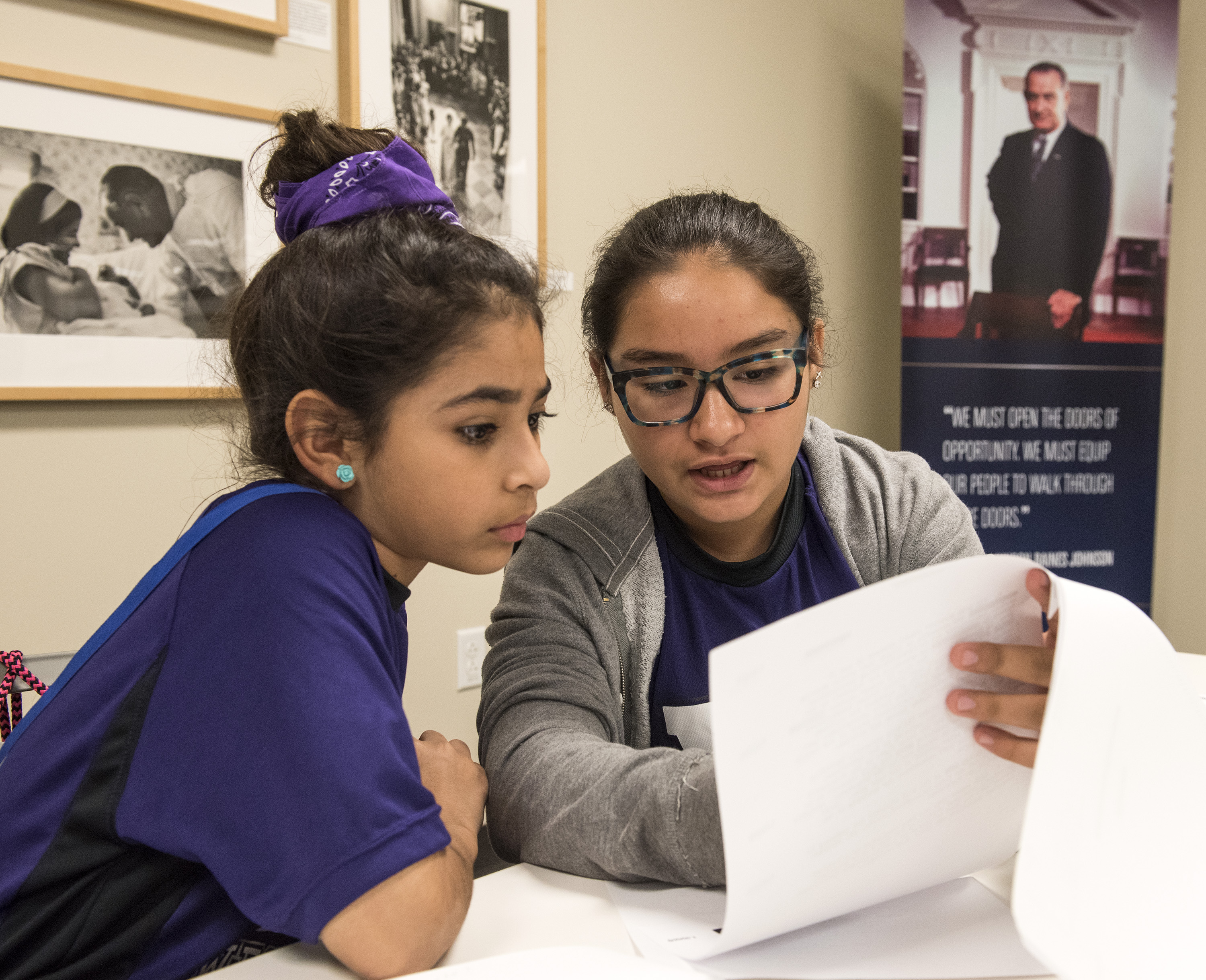 Two female students look closely at a paper during their immersive classroom experience at the LBJ Library.
