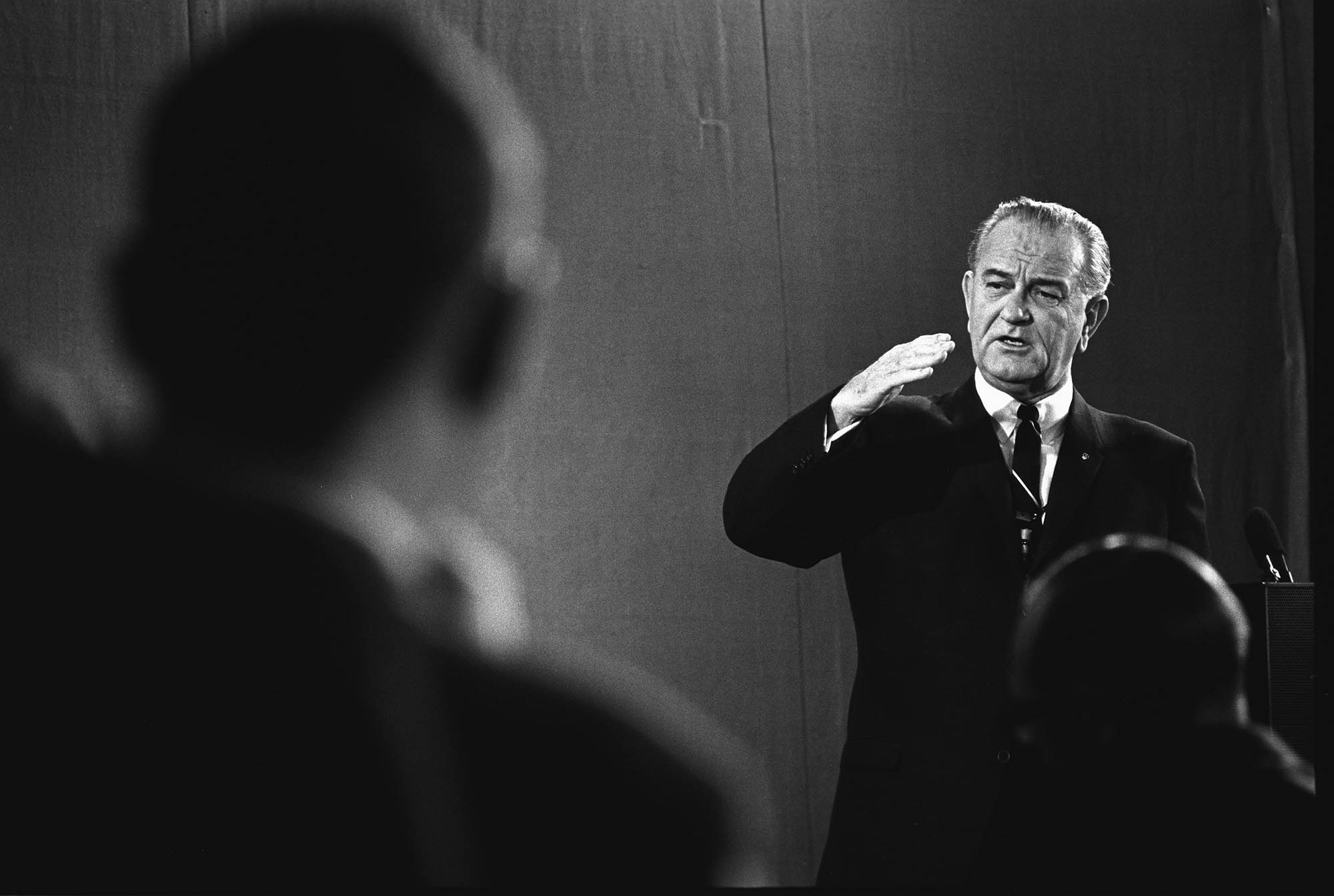 Gesturing with his right hand, President Johnson speaks to an audience.