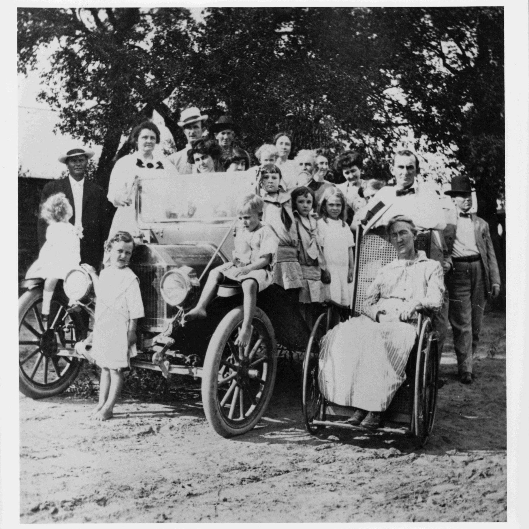 Group photo of the Johnson family with all posed around an automobile.