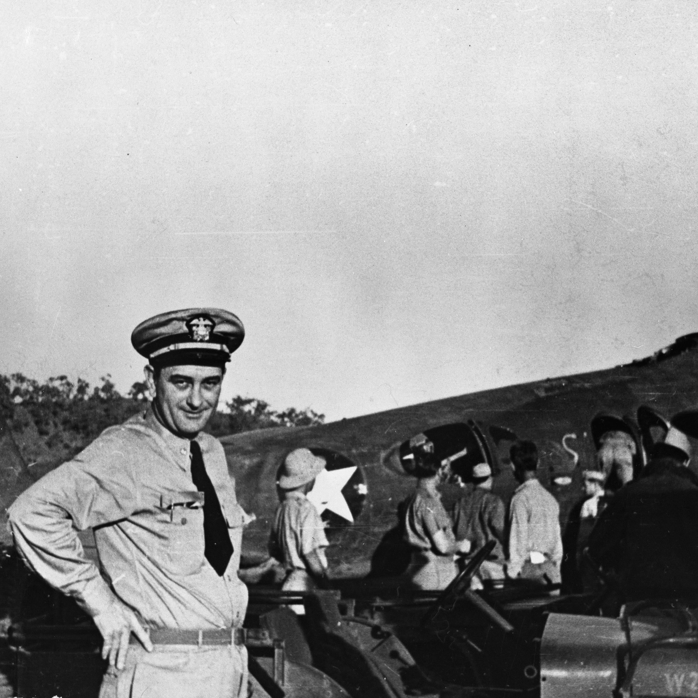 Lt. Commander Lyndon. B Johnson, dressed in his Naval uniform, poses in front of an aircraft at the Seven Mile Air Drome, New Guinea.