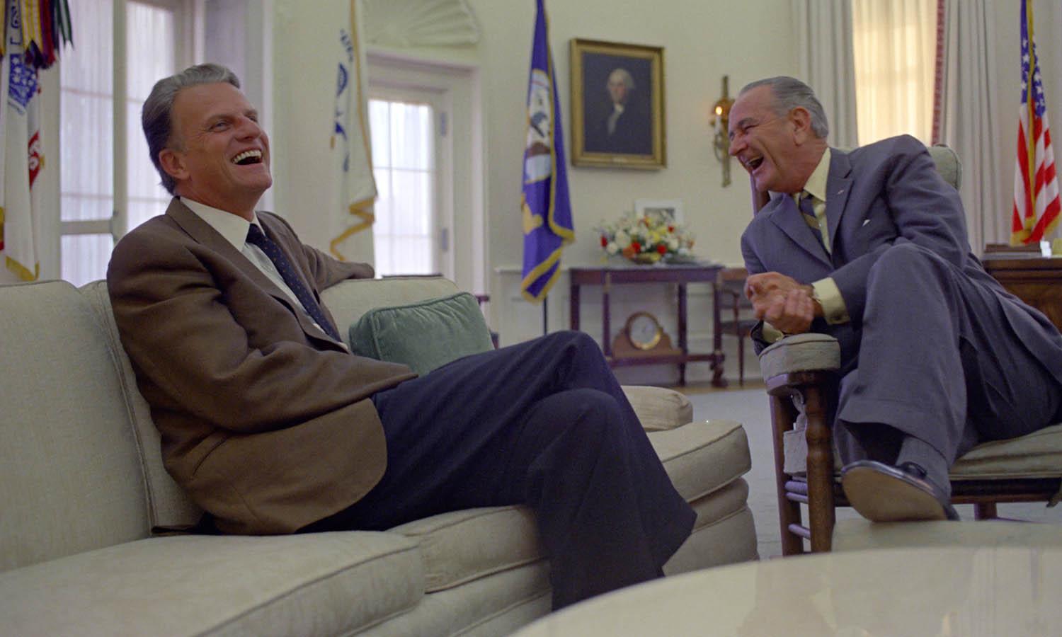 Rev. Billy Graham and President Lyndon B. Johnson share a laugh while meeting in the Oval Office.